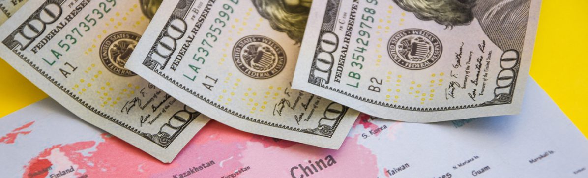 Imagem de uma mapa com o recorte da China e notas de dólar
